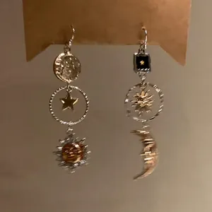 Close-up detail of asymmetric sun and moon tassel ear hooks with a vintage metal finish.