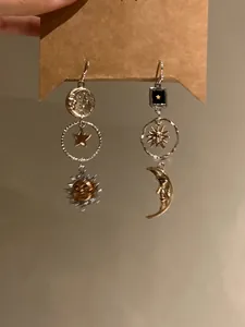 Detail of asymmetric celestial sun and moon drop earrings with silver and gold tones