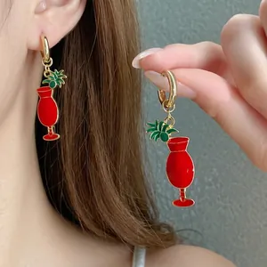 Élégantes boucles d'oreilles cocktail en émail rouge avec détail ananas sur modèle