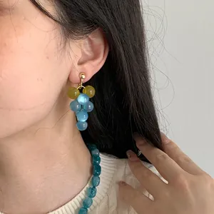 Detailed view of a model wearing cute light blue resin grape cluster earrings forest style