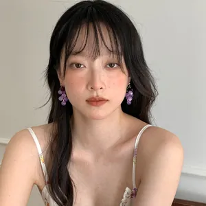 Detail view of a model wearing sweet purple resin grape earrings in a forest style