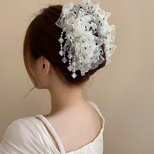 Détail d'une pince à cheveux en dentelle blanche avec pois noirs et glands en cristal.