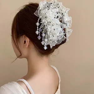 Pince à cheveux élégante en dentelle avec pompons en cristal sur un chignon