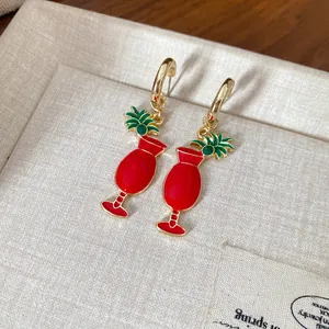 Détail des boucles d'oreilles pendantes en émail rouge en forme de verre à cocktail