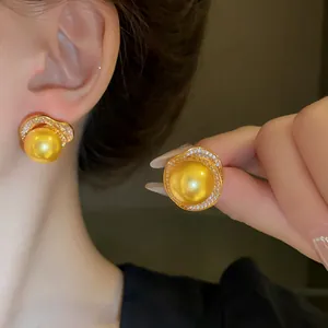 Vue détaillée d'élégantes boucles d'oreilles fleur en or avec perles jaunes et zircons brillants