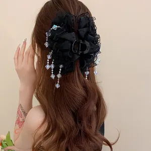 Vue détaillée d'une pince à cheveux élégante en dentelle noire avec glands de cristal