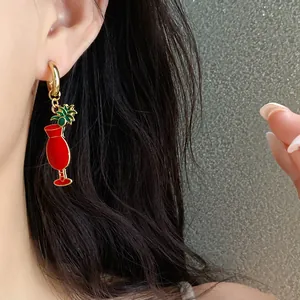 Gros plan d'une boucle d'oreille pendante en émail rouge en forme de verre à cocktail