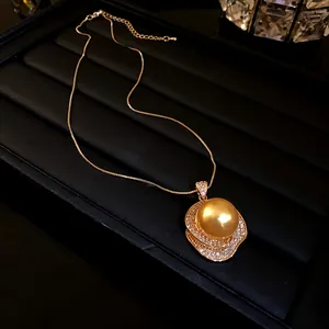 Détail d'un collier vintage français avec grande perle dorée et niveaux en zircon