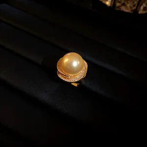 Vue rapprochée d'une bague de luxe avec perle dorée et détails de fleurs en zircon