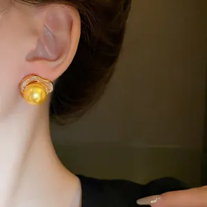 Détail élégant d'une boucle d'oreille rétro française avec perle dorée et zircon