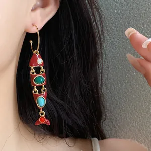 Gros plan détaillé de boucles d'oreilles pendantes en émail en forme de poisson porté