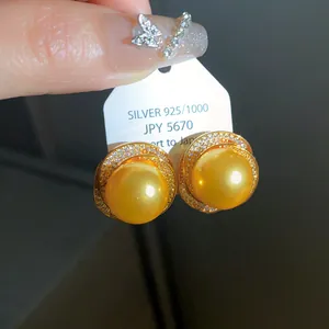 Gros plan de boucles d'oreilles perles dorées avec zircons sur étiquette en argent