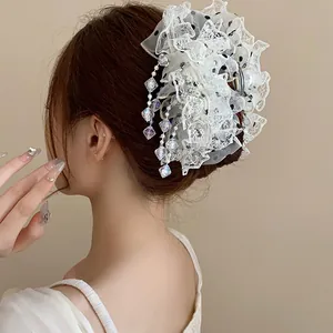 Vue arrière détaillée d'une pince à cheveux en dentelle blanche avec volants et glands.