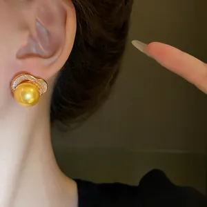 Détail d'une boucle d'oreille en perle dorée avec ornements en zircon sur un mannequin