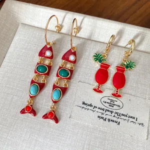 Vue détaillée des boucles d'oreilles créatives en émail rouge en forme de poisson et cocktail