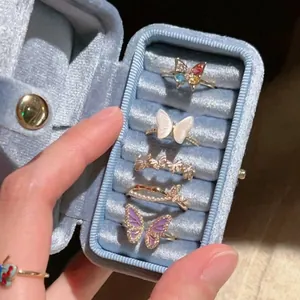 Detailed view of five butterfly rings with zircon and pearls in a blue velvet jewelry box