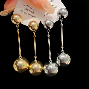 Close-up of gold and silver metallic double ball drop earrings with high polish finish