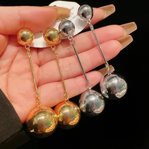 Macro detail showing glossy metallic ball tassel earrings in gold and silver finish options.