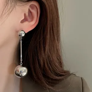 Detail shot of minimalist silver metal ball tassel earrings with a glossy mirror finish