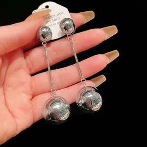 Macro view of silver-tone metal ball tassel earrings with a brilliant shiny mirror finish