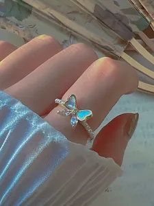 Close-up of zircon butterfly ring with iridescent wings and beaded band on finger