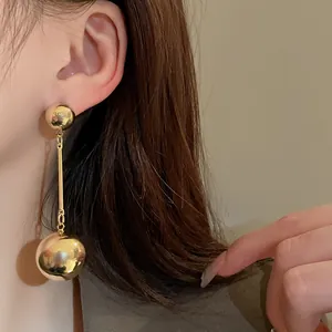 Elegant close-up shot of a minimalist gold metal ball tassel earring on model ear.
