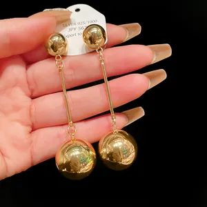 Detailed view of elegant golden metal long drop earrings featuring shiny double ball design