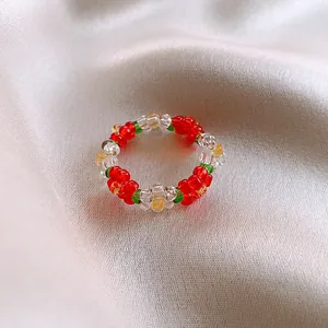 Macro view of a colorful handmade beaded flower ring resting on elegant white satin fabric
