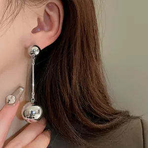 Detailed side view of silver mirror-finish ball tassel earrings on an Asian model