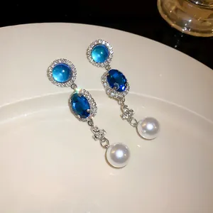 Detailed view of elegant French retro drop earrings with blue stones and pearls