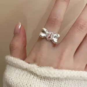 Detailed view of a stylish silver bow ring with pink zircon worn on a finger