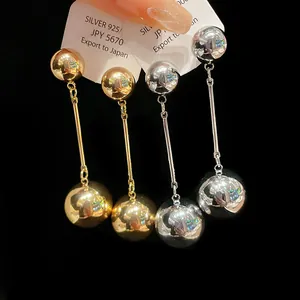 Macro detail of metallic gold and silver ball tassel earrings with S925 silver studs
