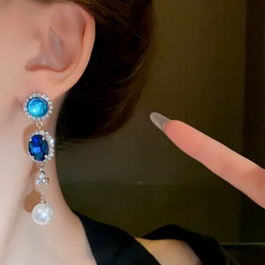 Detailed view of French vintage style blue gemstone and pearl drop tassel earrings.