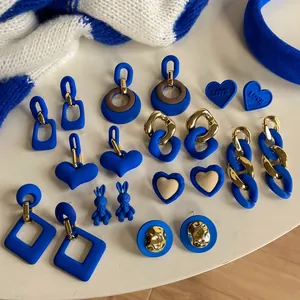 Collection of matte Klein blue and gold earrings in various geometric and heart shapes