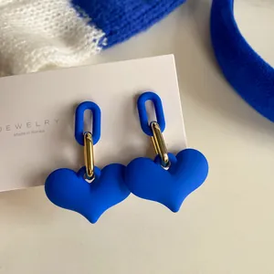 Close-up of vintage-style Klein blue heart-shaped earrings with elegant gold accents