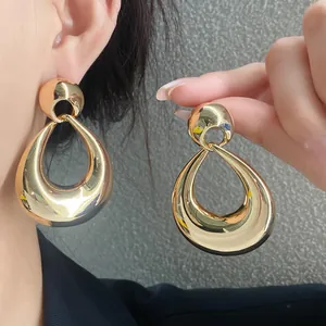Gros plan de boucles d'oreilles gouttes dorées avec une finition métallique polie.