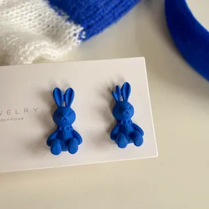 Close-up of Klein Blue bunny stud earrings with matte finish and stitch details.