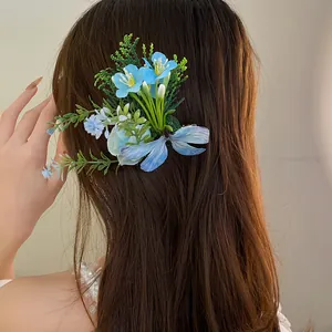 Close-up detail of a blue fabric flower hair clip worn on long brown hair, forest style