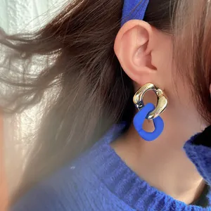 Detailed view of stylish Klein blue and silver chain link earrings on a model's ear.