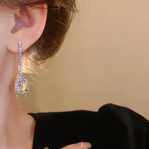 Close-up detail of elegant French style water drop rhinestone dangling earrings on a model