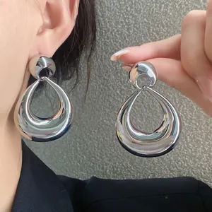 Boucles d'oreilles pendantes en métal argenté avec design géométrique audacieux.