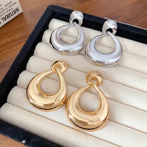 Boucles d'oreilles géométriques en forme de goutte dorées et argentées sur plateau velours