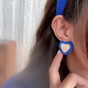 Detailed close-up of Klein blue heart earrings with soft velvet texture on model's ear