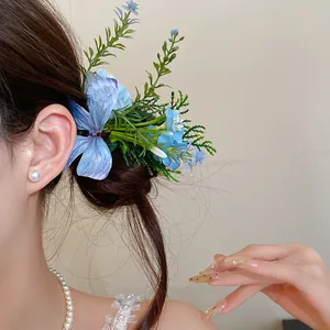 Elegant blue fabric flower hair clip with forest style leaf details worn by model