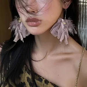 Elegant purple feather tassel drop earrings worn by a model in a close-up fashion shot