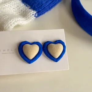 Detailed close-up of Klein blue heart earrings with cream plush center on white card