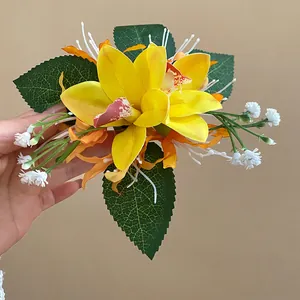 Close-up of yellow orchid fabric flower hair clip with green leaves and white buds