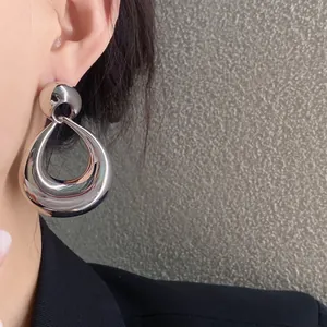 Gros plan de boucles d'oreilles pendantes en métal argenté portées par un mannequin de mode