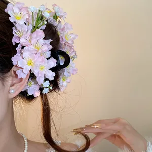 Close-up of pink fabric flower hair clip on model's hair in a sweet forest style.