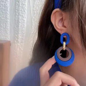 Close-up of vintage Klein blue geometric drop earrings worn by a model in detail view